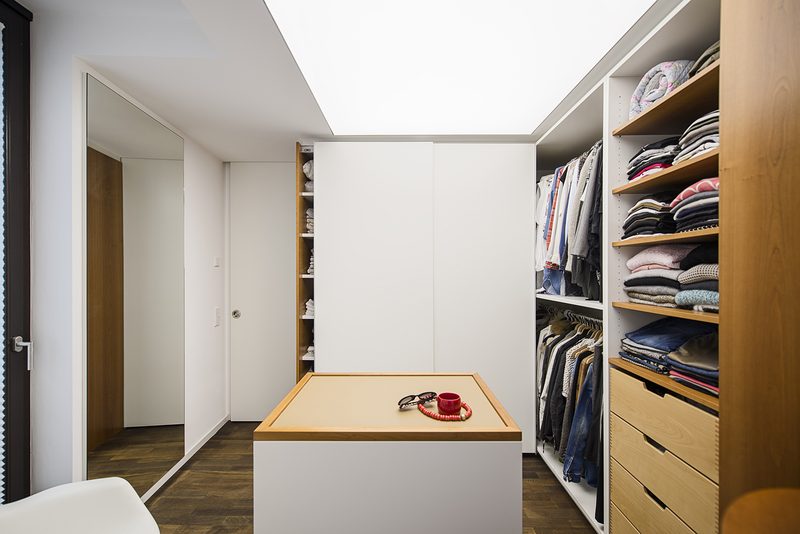 Privatwohnung, Ankleidezimmer: Schrankwand mit Holzregalen und Schubladen, Mittelblock und Lichtdecke