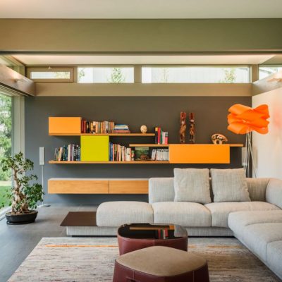 Privatwohnung, Wohnbereich mit Ecksofa, Wandregalen und oranger Stehleuchte